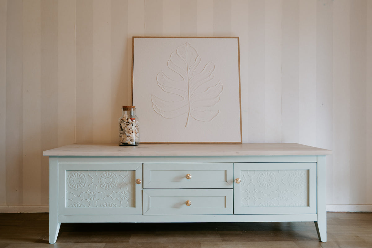 Light blue sideboard with decorative elements against a neutral wall.